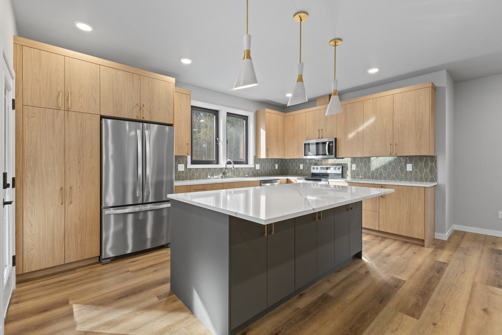 Southwest Florida light wood kitchen with quartz island and pendant lighting by The Kitchen Depot